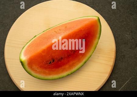 Slice of water melon on a bright wooden board on a black background. Stock Photo