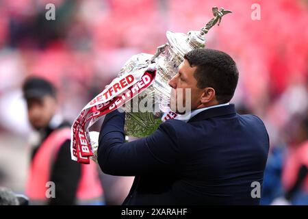 Wigan Warriors head coach Matt Peet celebrates with the trophy in front of the fans after the Betfred Challenge Cup final at Wembley Stadium, London. Picture date: Saturday June 8, 2024. Stock Photo