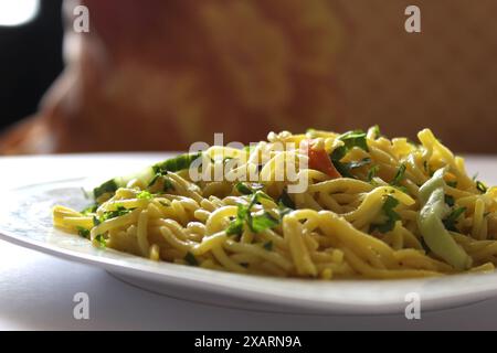 Indonesian fried noodles, bami goreng, mie goreng on a white plate with selective focus and bokeh background. Stock Photo