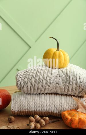 Autumn composition with stack of stylish sweaters, pumpkins and acorns on wooden background Stock Photo
