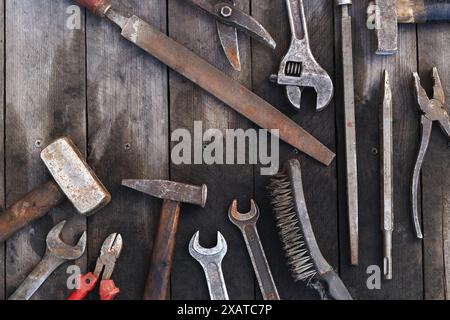 Old work tools on a plank wooden background, top view. Hammers, flat file, tin snips, brush, adjustable wrench and wrench. Hand tool. Builder's Day or Stock Photo