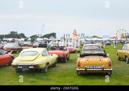 Classic cars parked in Revival Car Show with Helter Skelter in background, located in 'Over the Road' at Goodwood Revival, Chichester, West Sussex, UK Stock Photo