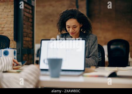 Group of female managers sitting in open office while working on digital tablet and laptop Stock Photo