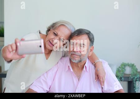 Older couple take a selfie with cell phone sitting at home Stock Photo