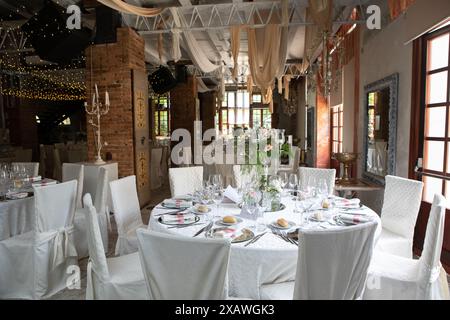 Elegant wedding reception venue decorated with flowers and candles inside a building Stock Photo