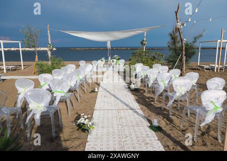 Elegant white wedding chairs are set up on a sandy beach for a wedding ceremony Stock Photo