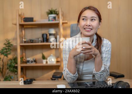 A young woman drinks coffee while working at home Stock Photo