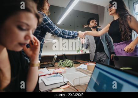Business team in meeting at modern office with two colleagues shaking hands Stock Photo