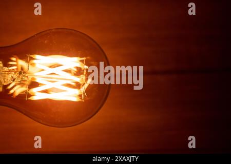 A60 E27 Edison light bulb, also known as filament light bulb on wooden background. Stock Photo