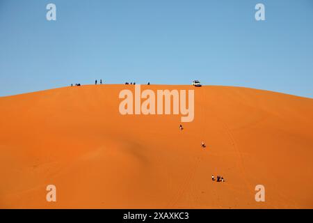 Tourists climbing a sand dune of the Grand Erg Occidental at Taghit in Western Algeria Stock Photo