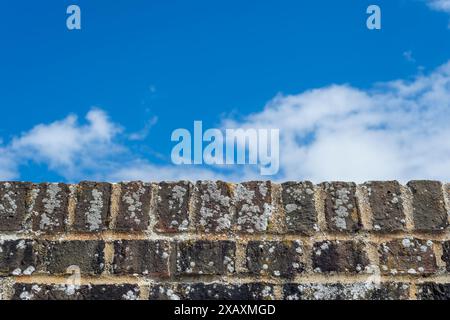 Top of a brick wall with a blue sky background Stock Photo