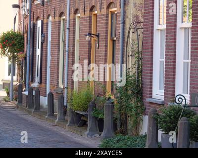 Quiet city street with traditional brick houses, ornate lanterns and climbing plants, Doesburg, Netherlands Stock Photo