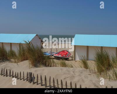 Wooden huts on the beach, surrounded by sand dunes and lifeboats, with the sea in the background, oostende, Belgium Stock Photo