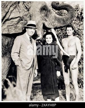 Edgar Rice Burroughs (1875-1950) with Maureen O'Sullivan (1909-1960) and Johnny Weissmuller (1904-1984) who portrayed Jane Parker and Tarzan in MGM’s adaptation of his 1912 novel Tarzan of the Apes. Photograph taken on the set of Tarzan the Ape Man (1932). Note the false tusk and ear added to the Indian elephant used in the production to make them resemble African elephants. Credit: Private Collection / AF Fotografie Stock Photo