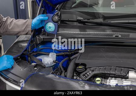 Car winter maintenance antifreeze control. Automobile mechanic tests car antifreeze liquid for winter and summer. Car wiper fluid controls and adding Stock Photo