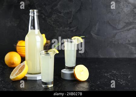 Bottle and shots of tasty Limoncello with rosemary on black background Stock Photo