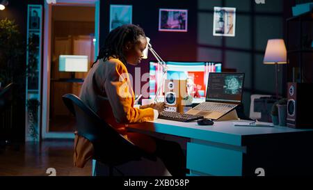African american girl uses artificial intelligence software for machine learning and cloud computing, terminal window programming language. IT student studying deep learning AI hardware. Camera B. Stock Photo