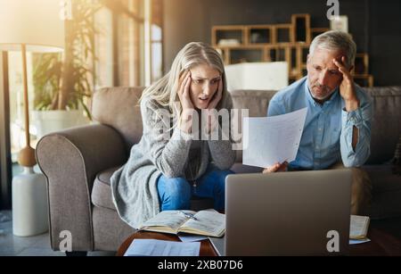 Frustrated couple, reading and documents with laptop in financial crisis, mistake or debt on sofa at home. Man and woman with paperwork in finance Stock Photo