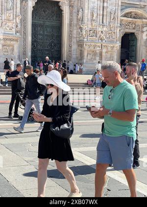 Woman in white hat and man with smartphones in Milan Piazza del Duomo. Tourists and maps. Traveling in Europe.  Stock Photo