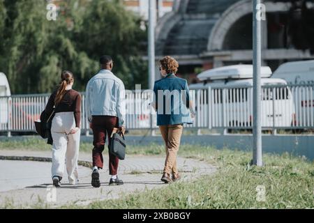Young professionals walking together in an urban setting, engaging in conversation Stock Photo