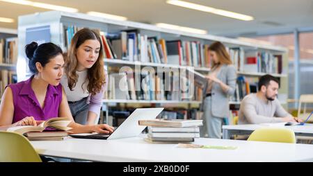Two female colleagues working on joint project in library Stock Photo