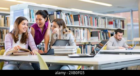 Three female friends studying together at library Stock Photo