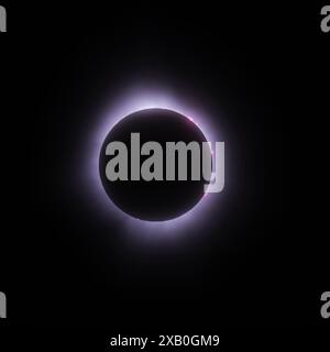 The total solar eclipse shows the suns corona and a number of orange solar flares, while the sun is completely black. Stock Photo