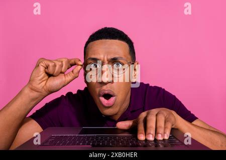 Photo portrait of handsome young guy typing keyboard frightened wear trendy violet outfit isolated on pink color background Stock Photo