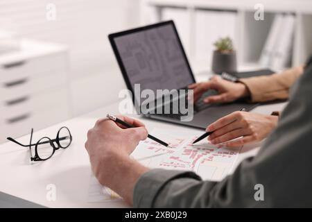 Cartographers working with cadastral map at white table in office, closeup Stock Photo