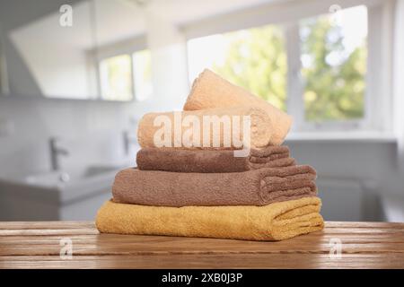 Stack of fresh towels on table against blurred bathroom interior Stock Photo