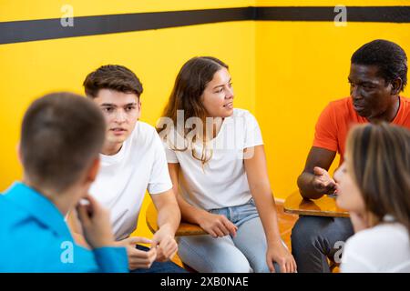Friendly adult students chatting cheerfully while sitting in classroom Stock Photo