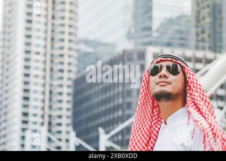 Handsome modern Arabian man using holding smart tablet. Arab Man Using smartphone calling while walking in the city. Business success concepts. Stock Photo