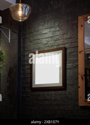 Mockup wooden square picture frame with mount, for add photo, artwork hanging on black brick wall at room corner. Blank white space on brown wood fram Stock Photo