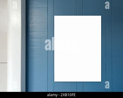 Mockup empty white vertical poster on vintage blue wooden door and white wall background, minimal style. Blank poster template on painted wood, for ad Stock Photo