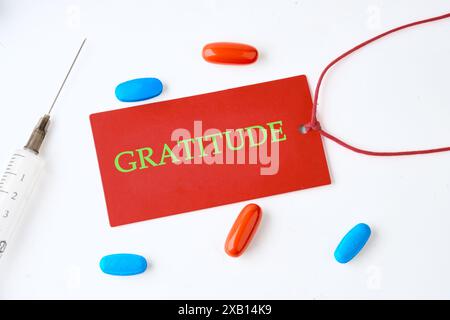 Top view of words GRATITUDE written on a red card on a light background with pills in the composition Stock Photo