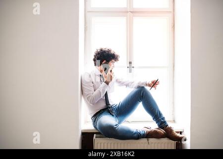 Young businessman working on new project in a startup company office, making phone call. Working in co-working space. Stock Photo