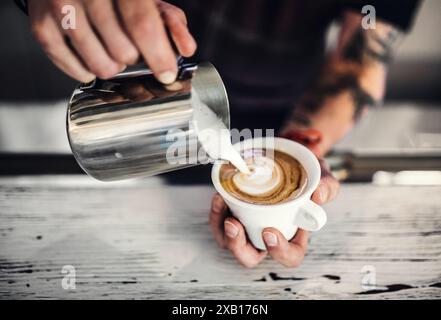 Close up of barista working in coffee shop, preparing coffee. University student working part-time in cafe. Stock Photo