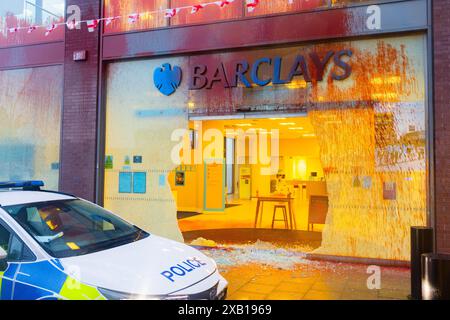 Bury, UK. 10 JUN, 2024. Direct action group target Bury branch of Barclays bank on Central Street. The direct action group have targeted other branches in recent weeks and on this occasion smashed windows and sprayed the building with red paint as well as caused damage to ATM machines. Credit Milo Chandler/Alamy Live News Stock Photo