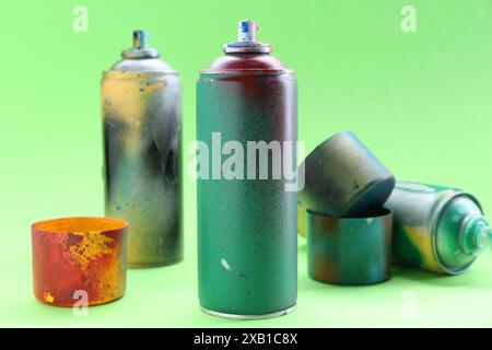 Spray paint cans with caps on green background, closeup Stock Photo