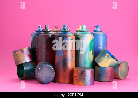 Many spray paint cans with caps on pink background Stock Photo