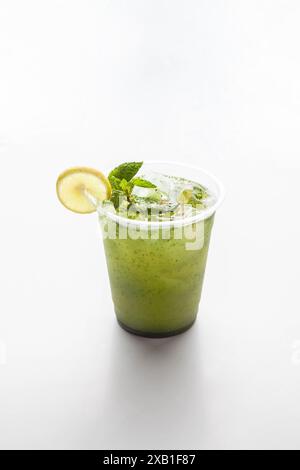Mint lemonade shikanjabeen served in a plastic to go cup with mint leaves ice cubes and slice of lemon on a white background. Stock Photo