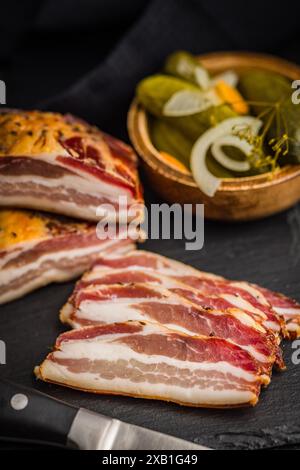 Closeup of Sliced Smoked Bacon on a Black Slate Cutting Board Stock Photo