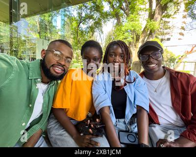 Four black student friends take selfie take break from studying while sit outside university library Stock Photo
