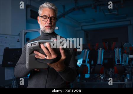 Automation engineer, technician holding remote controller of robotic arm. Concept of modern technology in industries, automated processes, robotics. Stock Photo