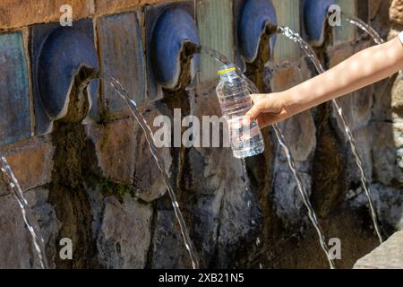 A child filling a plastic water bottle from a historic stone fountain Stock Photo