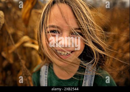 Up close portrait of happy young girl in sunny corn field Stock Photo