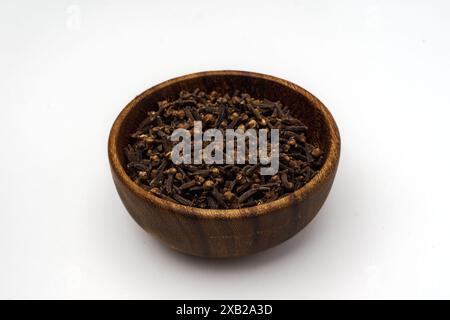 a wooden bowl full of cloves, isolated on a white background Stock Photo