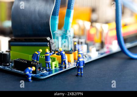 Tiny figurine workers repair and maintain a computer motherboard, symbolizing tech support Stock Photo