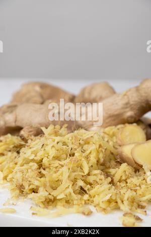 Pieces of finely grated fresh ginger root on kitchen board Stock Photo