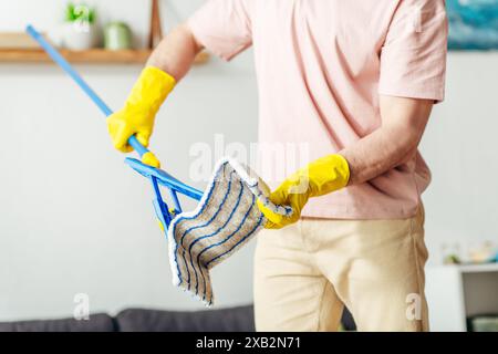 A man in cozy homewear meticulously mops the living room floor. Stock Photo